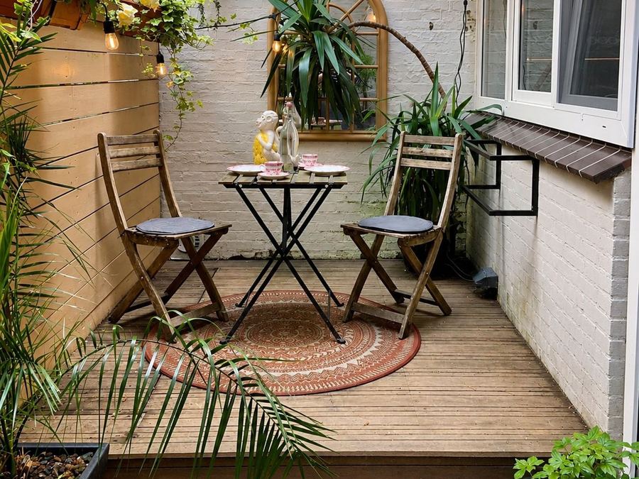 Houten binnenplaats met bistrotafel en veel planten