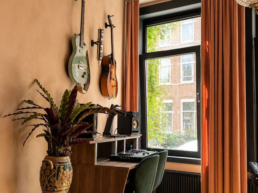 Muziek- en werkhoek met gitaren en planten bij het raam