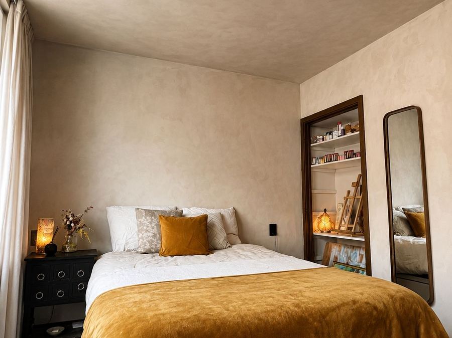 Slaapkamer met okergeel bed en antieke spiegel